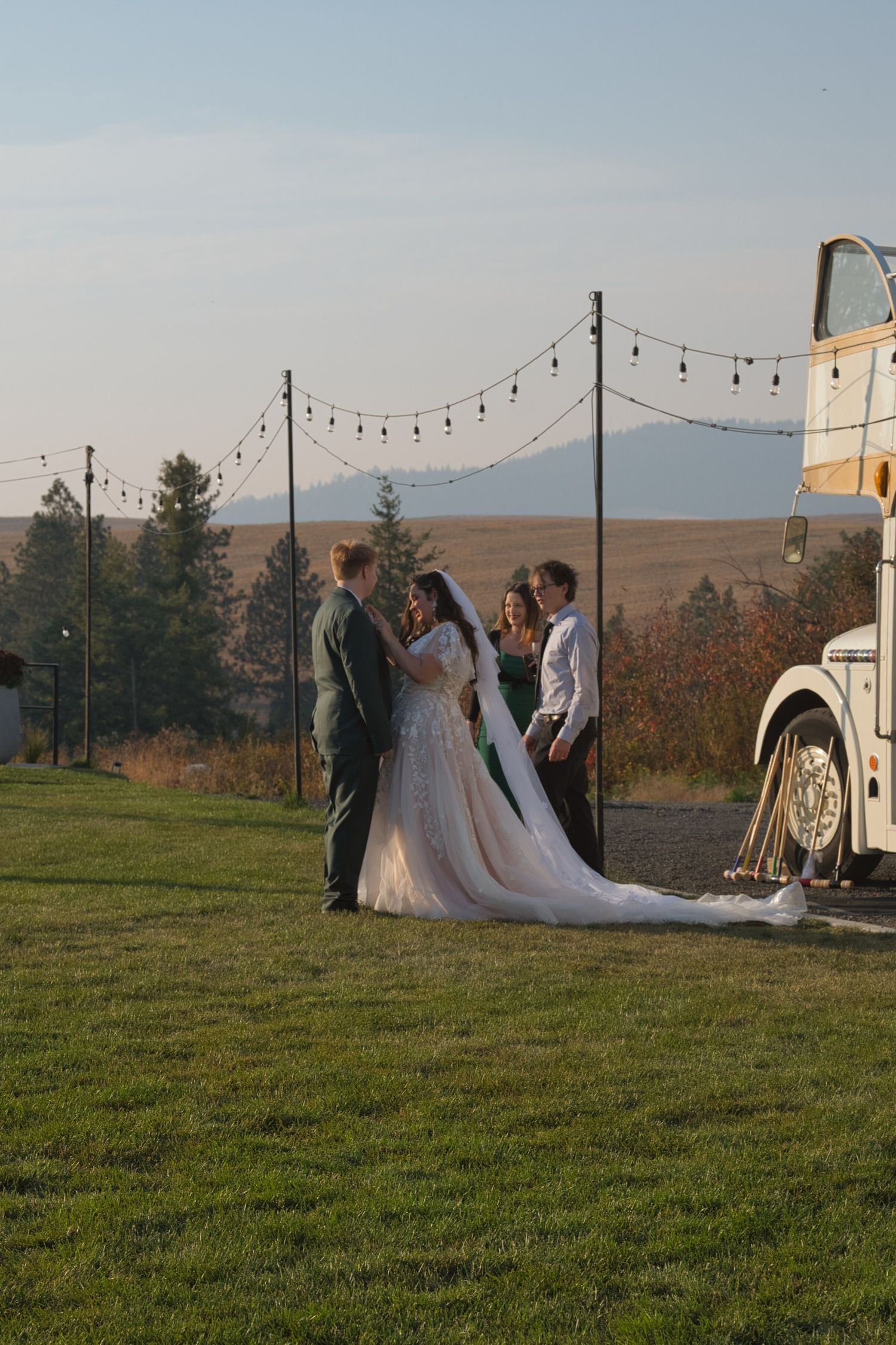 Bride fixes groom's suit while talking with another couple