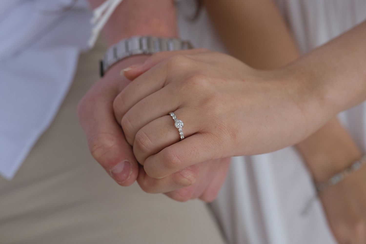 Close picture of engagement ring as couple holds hand