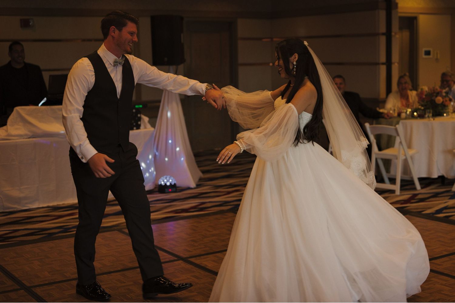 Groom twirls the bride as they dance together during the formal first dance during reception.