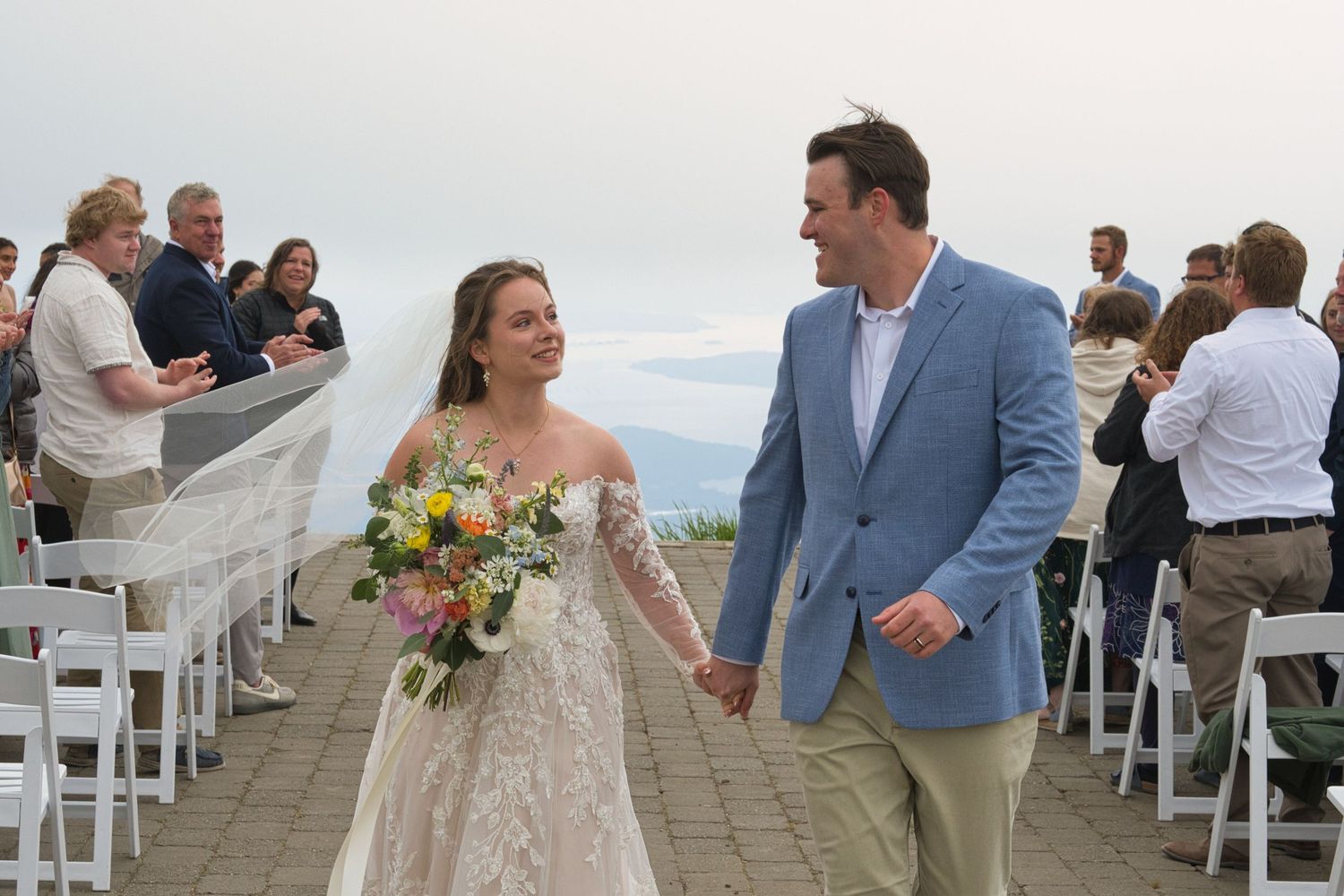 Candid moment of bride and groom smiling as they walk down the aisle in North Idaho