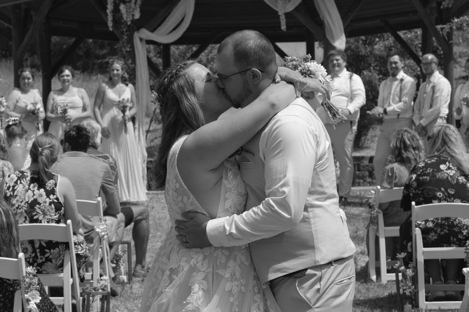 Bride and groom kissing as they walk away from wedding ceremony