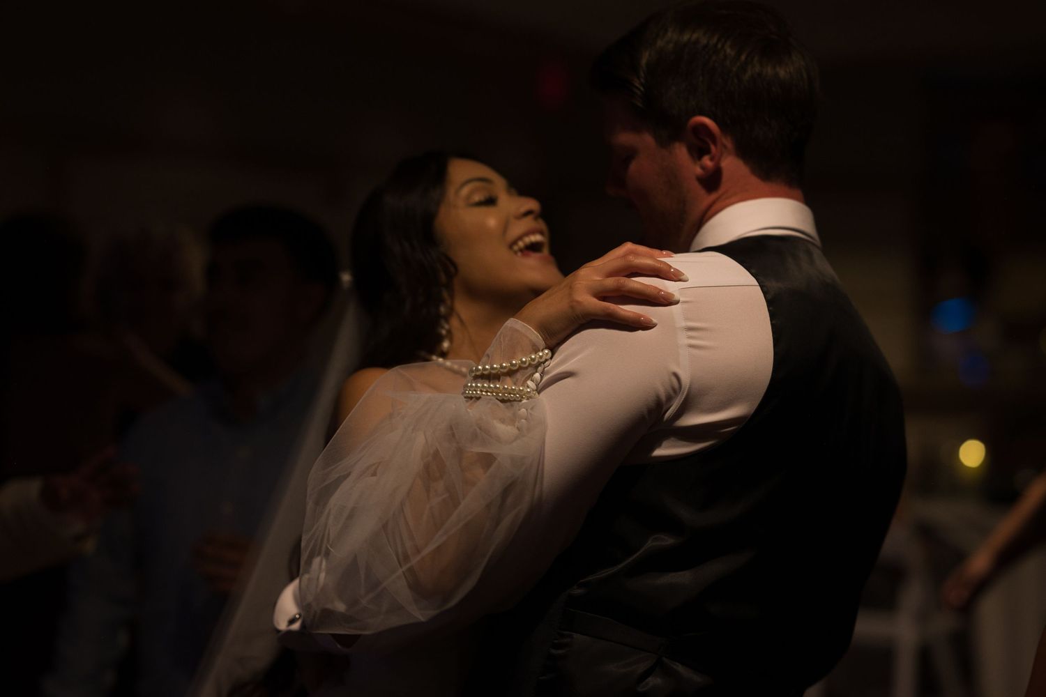 Bride's hand rests on grooms shoulder as he lifts her up while they sing along with a song.