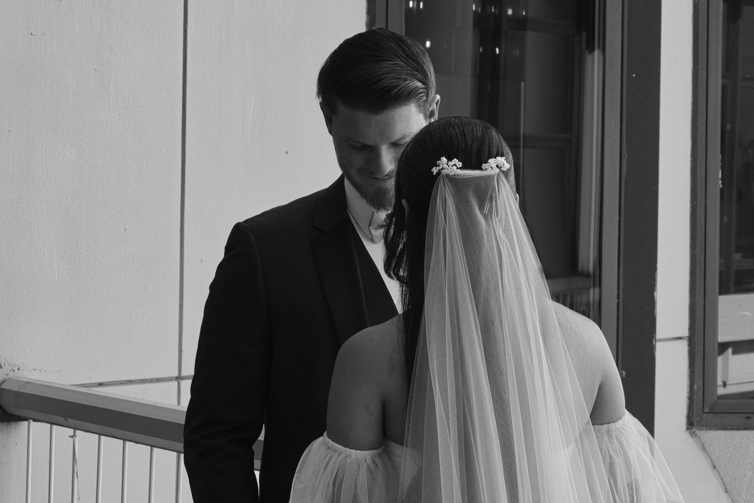 Black and white portrait focusing on the groom while the couple shares their first look.