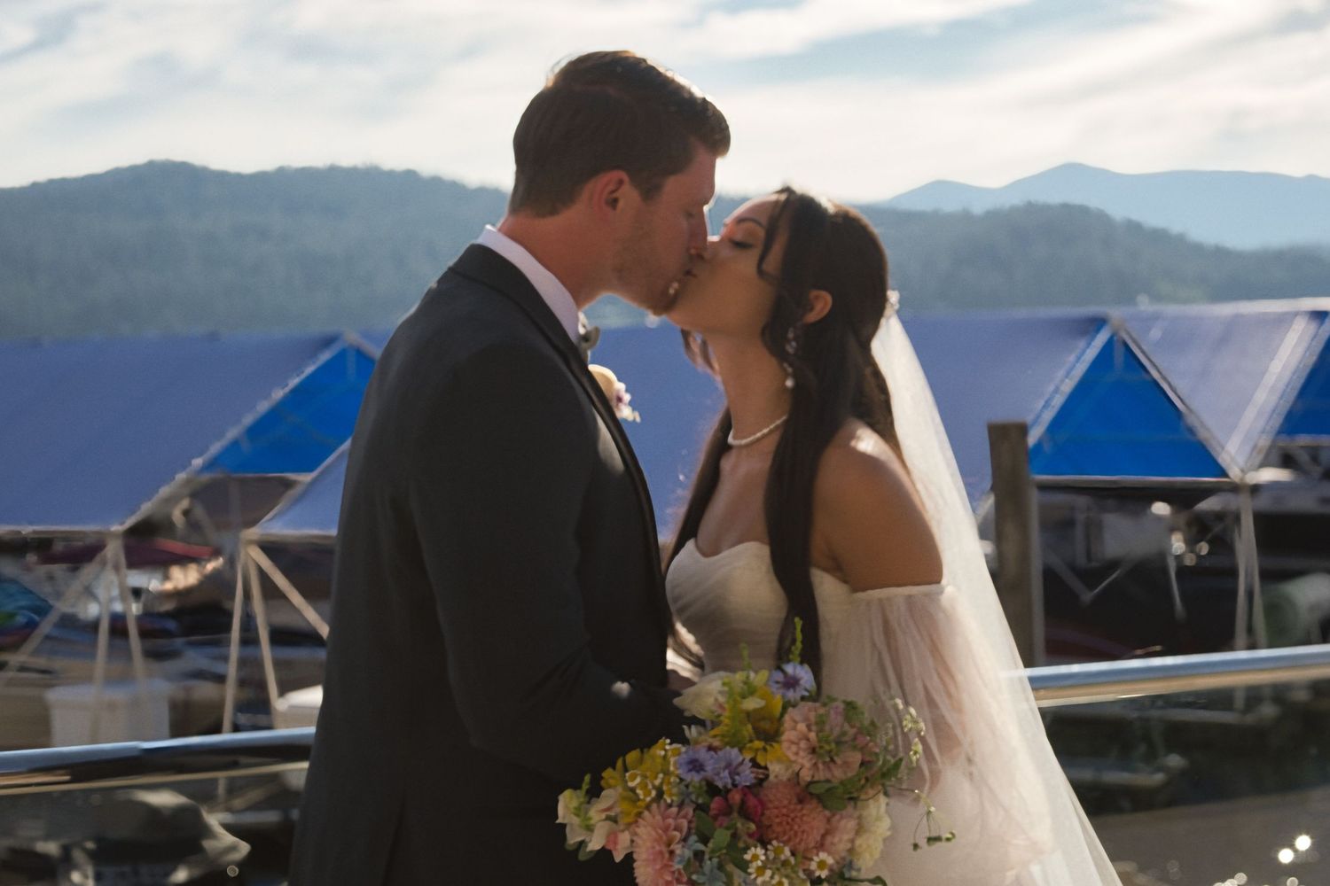 Bride and groom share a kiss as they take portraits outside in the sun in between wedding moments.