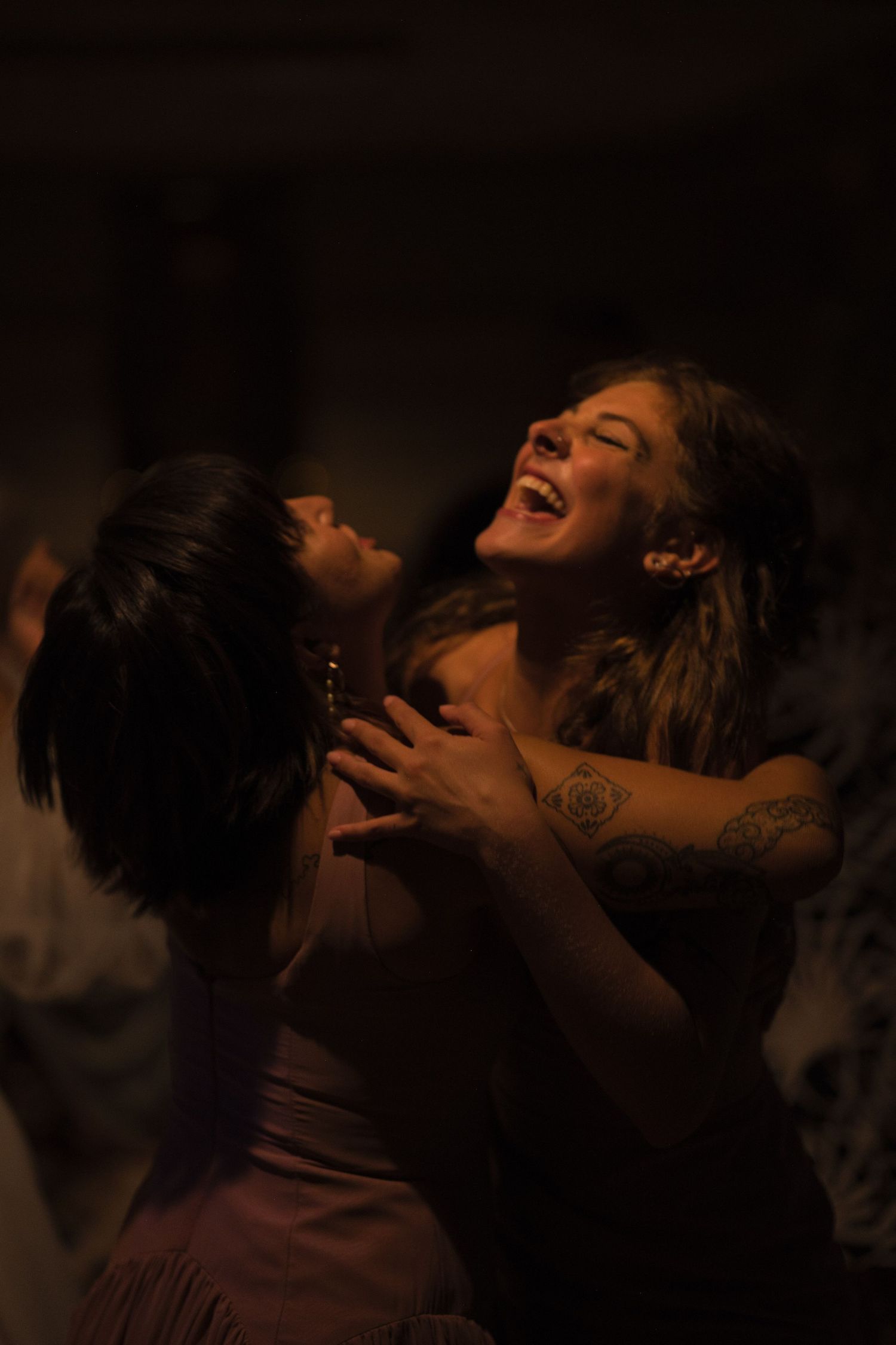 Bridesmaids hold each other close while they sing the lyrics to a song, dancing together.