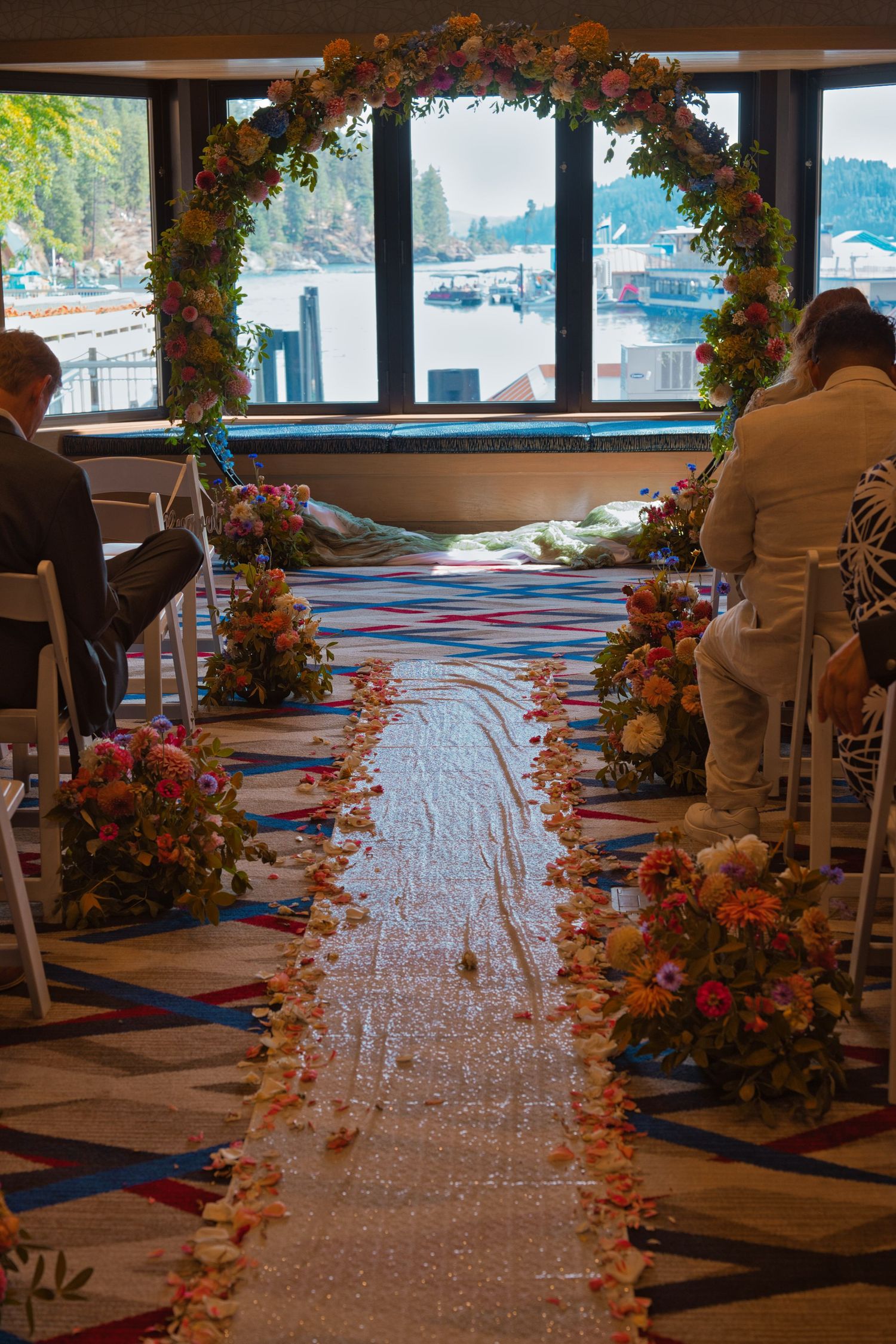 Detail picture focusing on the arch, covered in flowers, with flower petals lining the way to the front of the room.