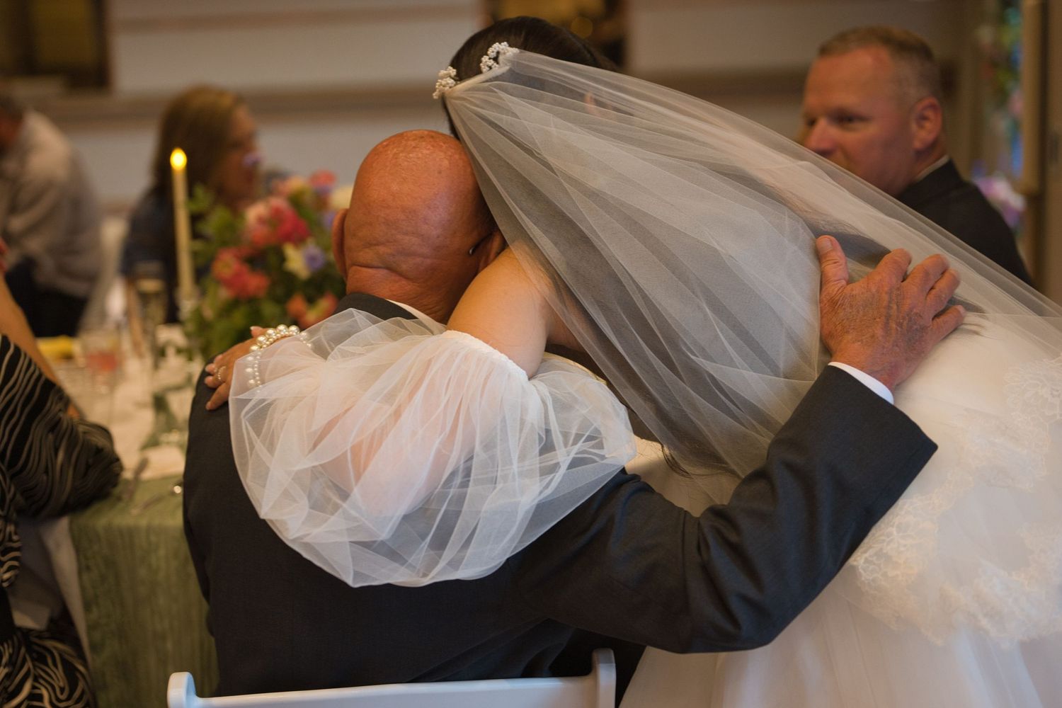 Bride leans down to hug groom's grandfather as they greet guests during the reception.