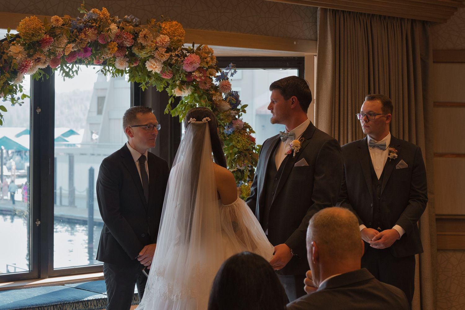 A picture focusing on the groom as he looks at the officiant, holding the bride's hands during the ceremony.