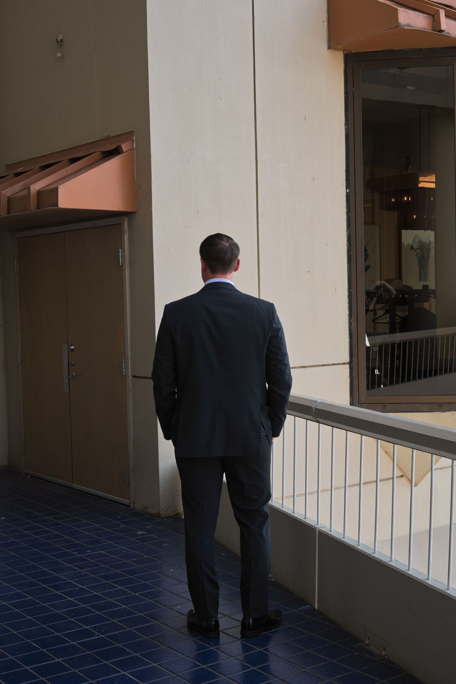Groom stands outside on a balcony as he waits for the bride for their first look together.