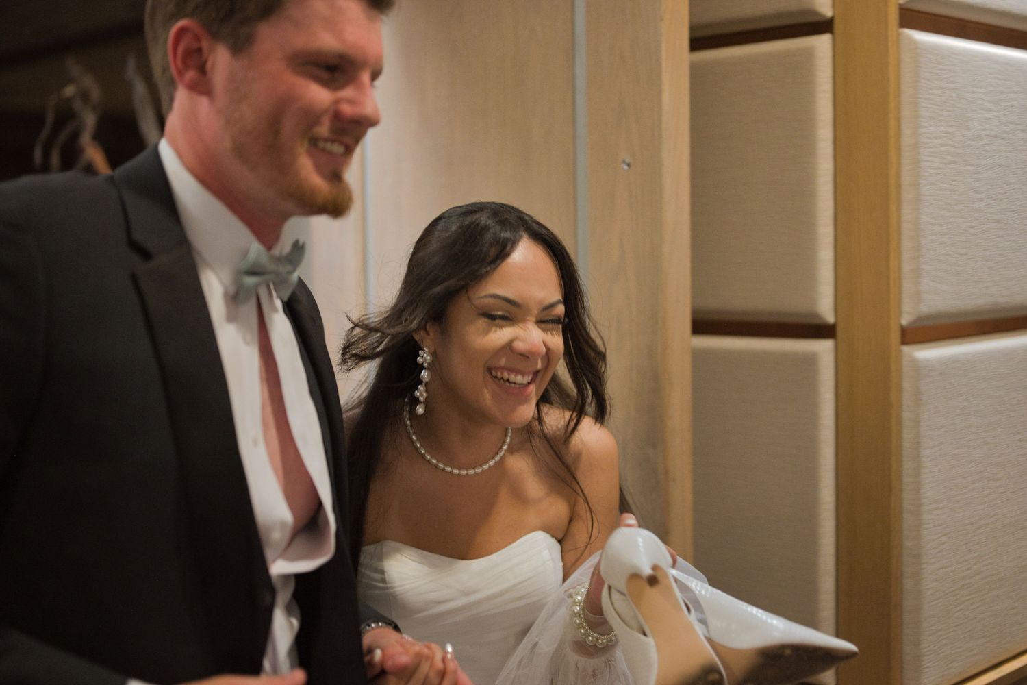 Bride and groom laugh and smile as they run away from their reception after guests send them off.