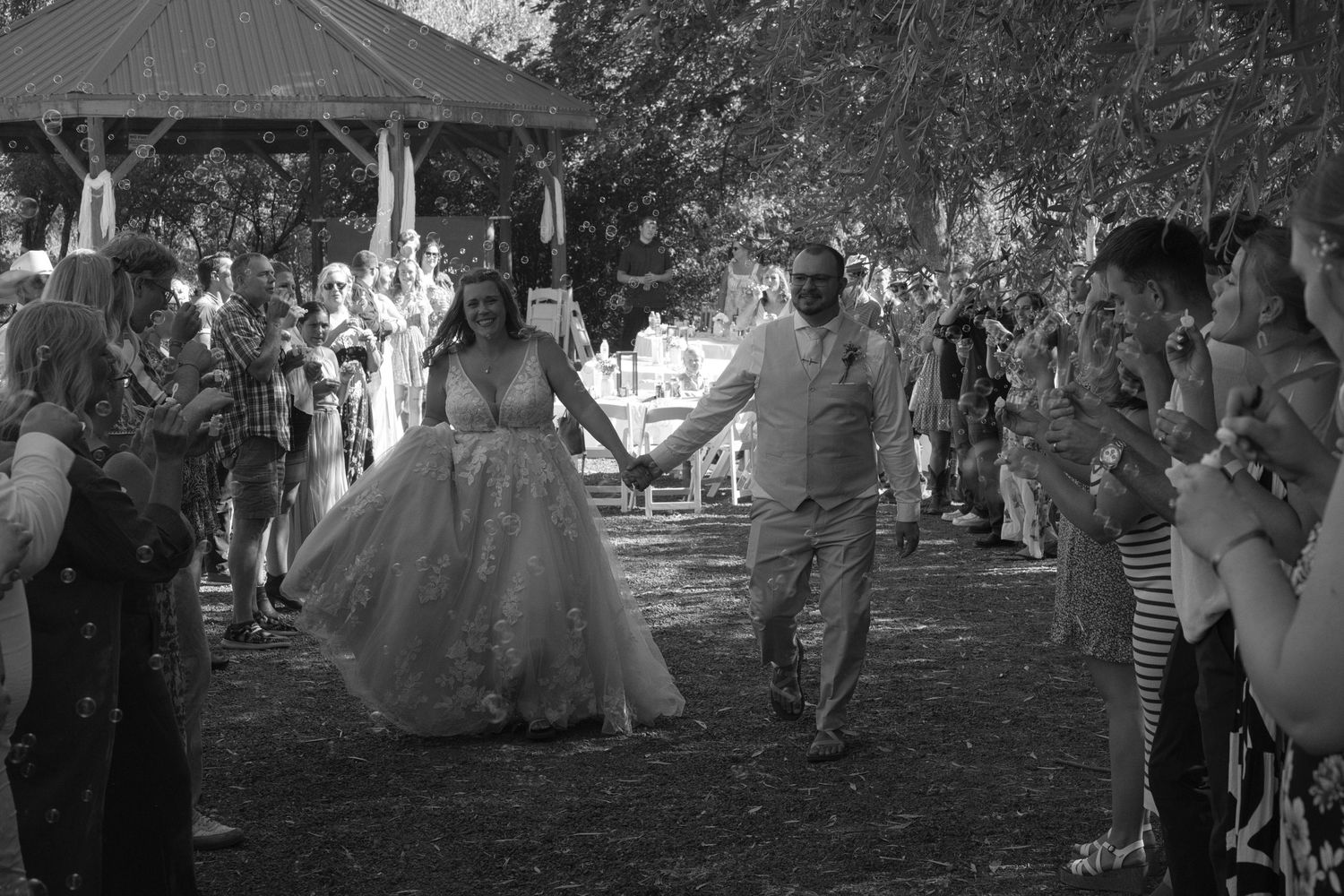 Bride and groom laughing as they walk between people as they leave the wedding