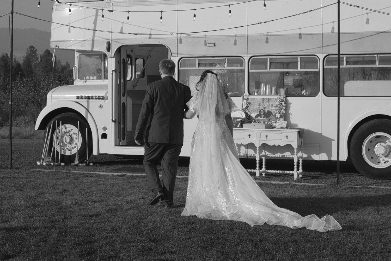 Bride and groom walk to old van as dress trails behind
