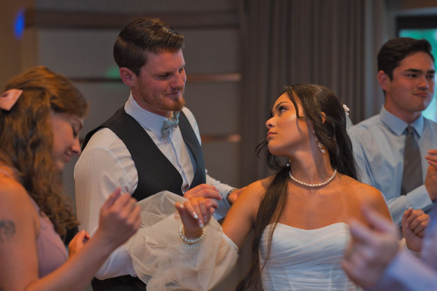 Bride looks over her shoulder at the groom as they move to the dance floor, surrounded by their friends and family.