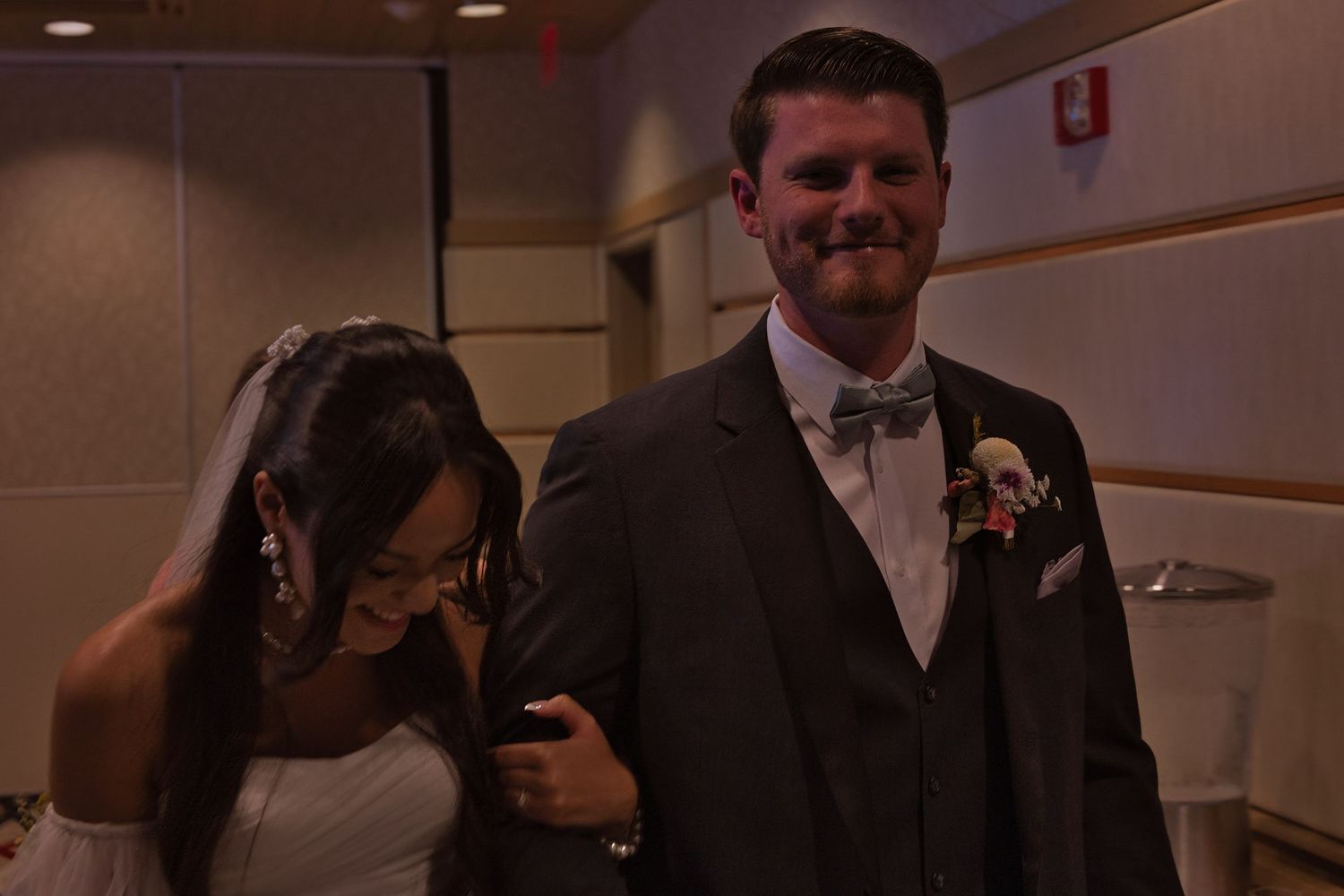 Bride and groom smiling joyfully as they walk away from their wedding ceremony as a married couple.
