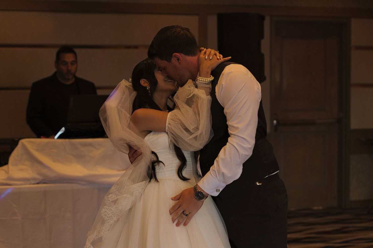 Bride and groom kiss during their first dance in the Coeur d' Alene Resort, the bride's hands are around the groom's neck.