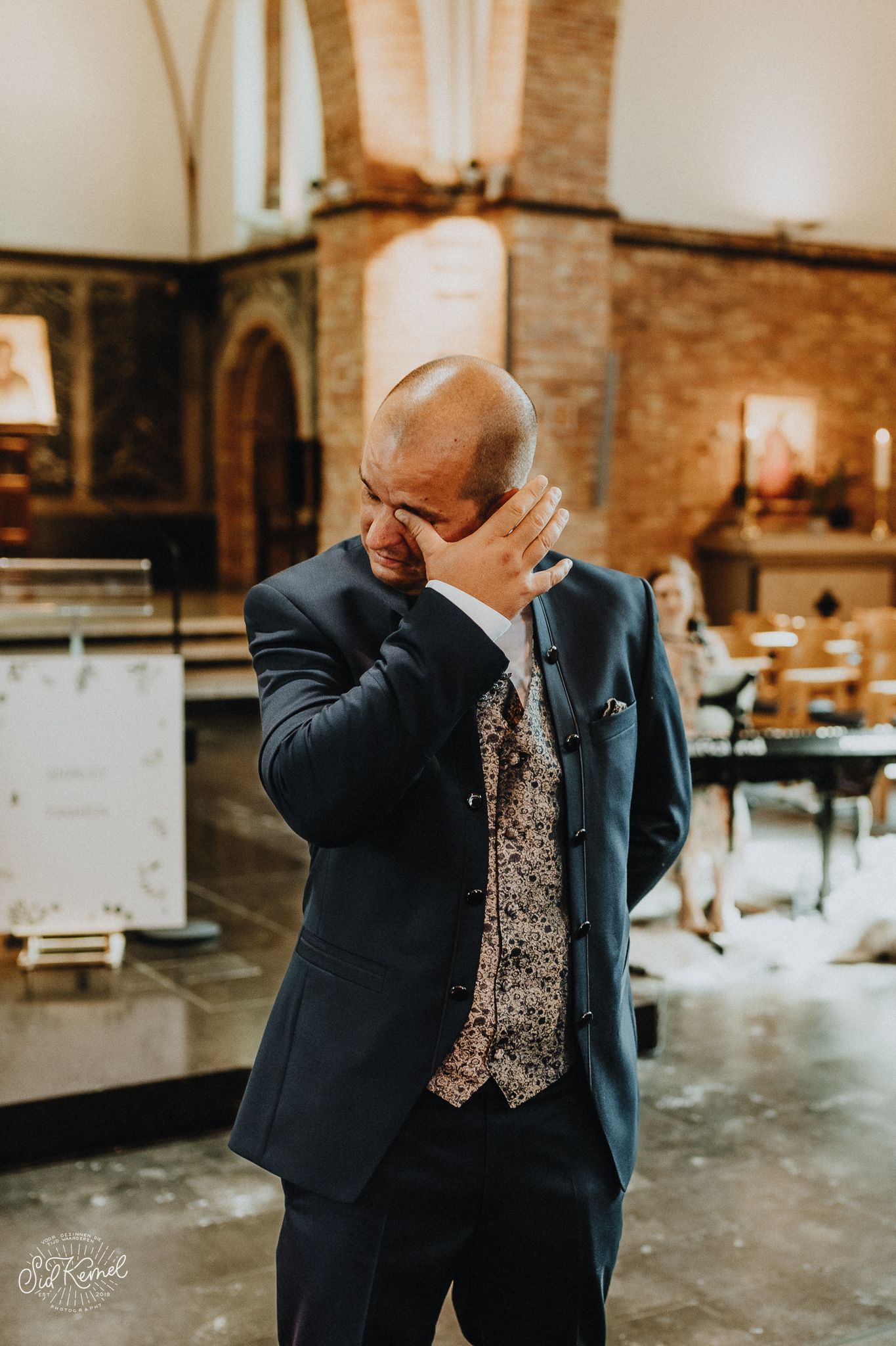 emotionele bruidegom die zijn traan weg veegt na het zien van zijn toekomstige vrouw in een kerkje gelegen in Oostende.