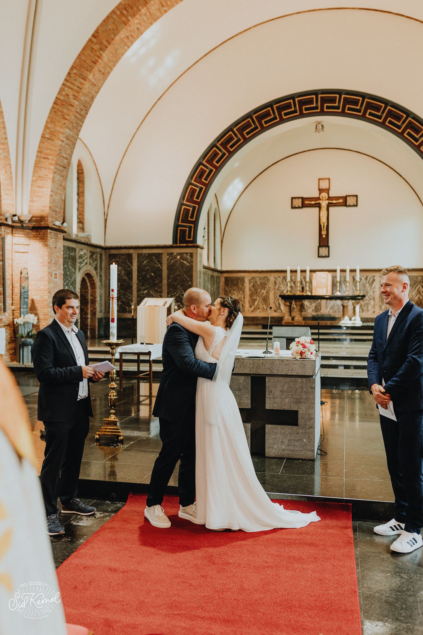 een koppel die net het ja woord hebben gegeven aan elkaar en spontaan de eerste kus geven in een kerkje in Oostende, west vlaanderen