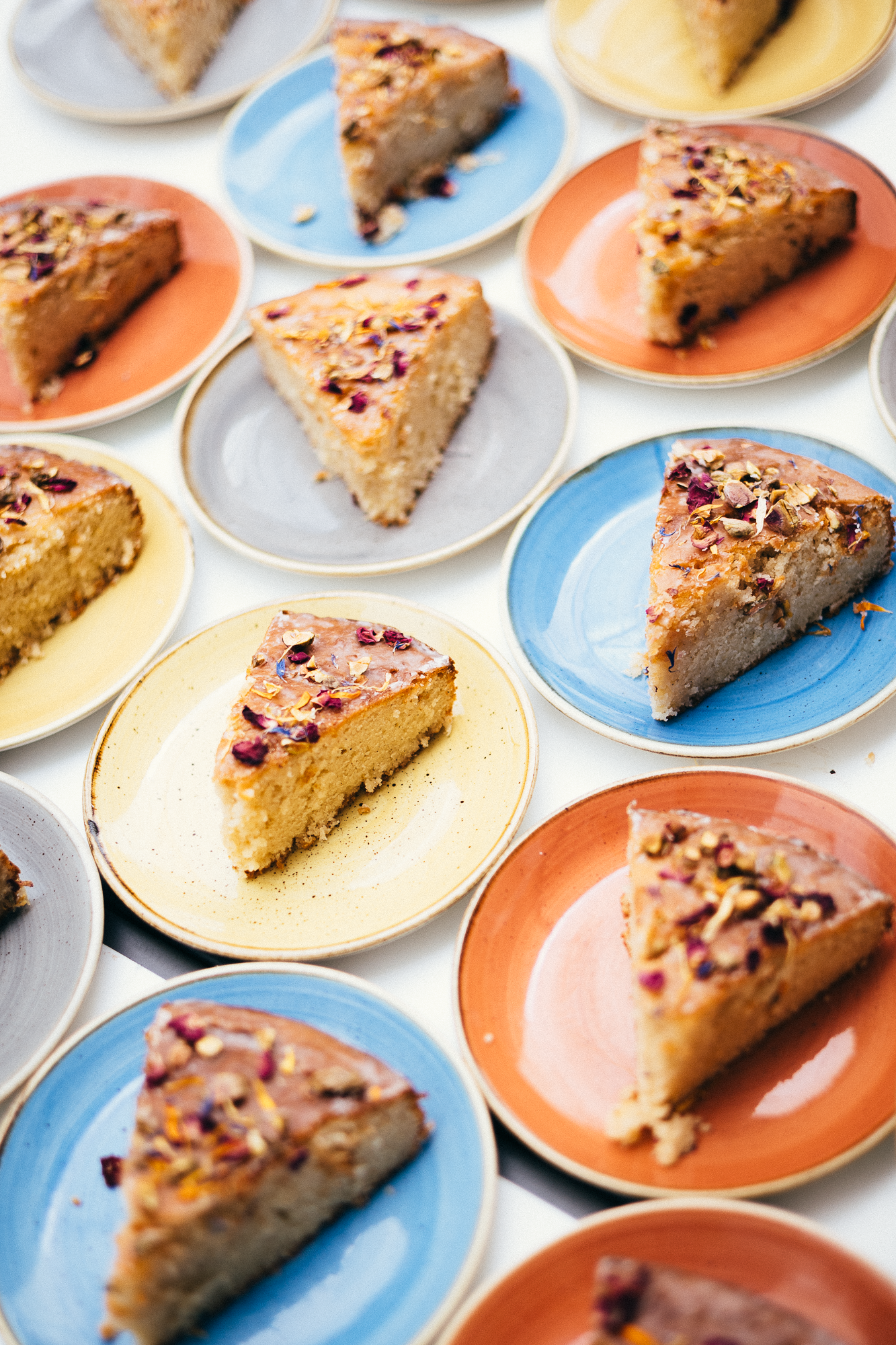 Triangular slices of decorated cake arranged on orange and blue plates.