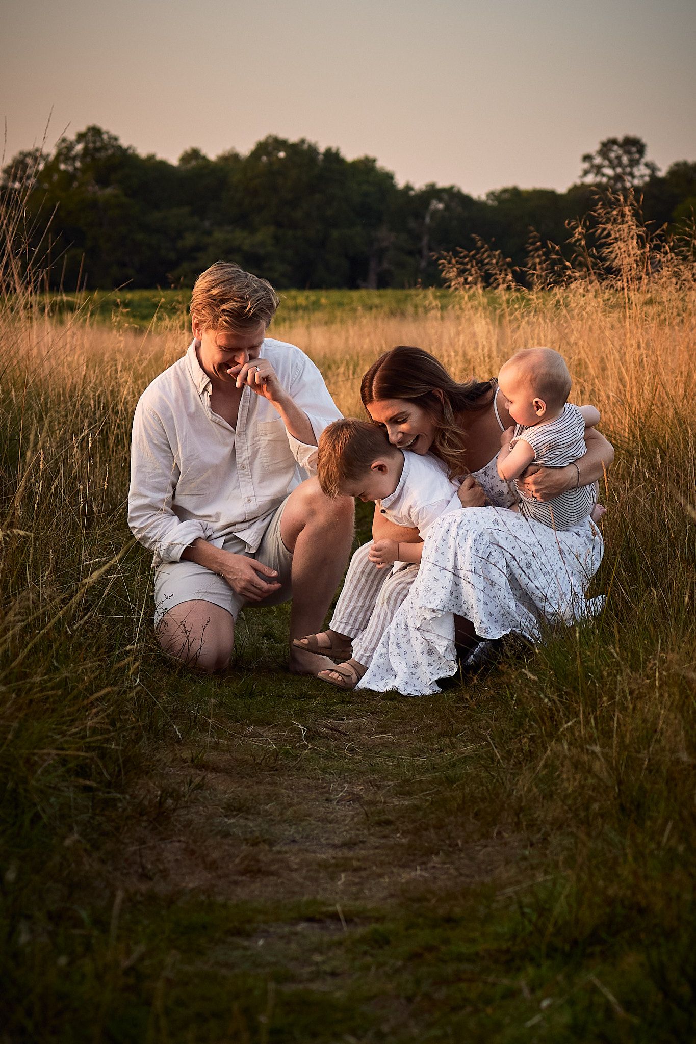 Family lying together in field during golden hour photography session.