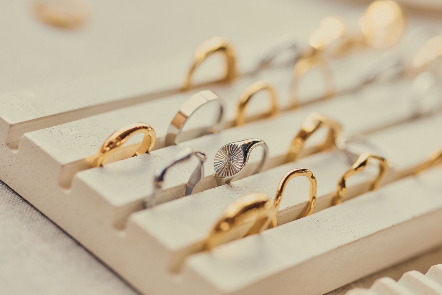 Collection of gold and silver rings displayed in a cream jewelry tray at a boutique showcase.