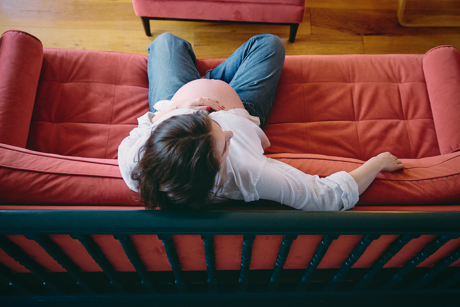 Someone relaxes on a comfortable red couch while reading a book in a cozy living room setting.