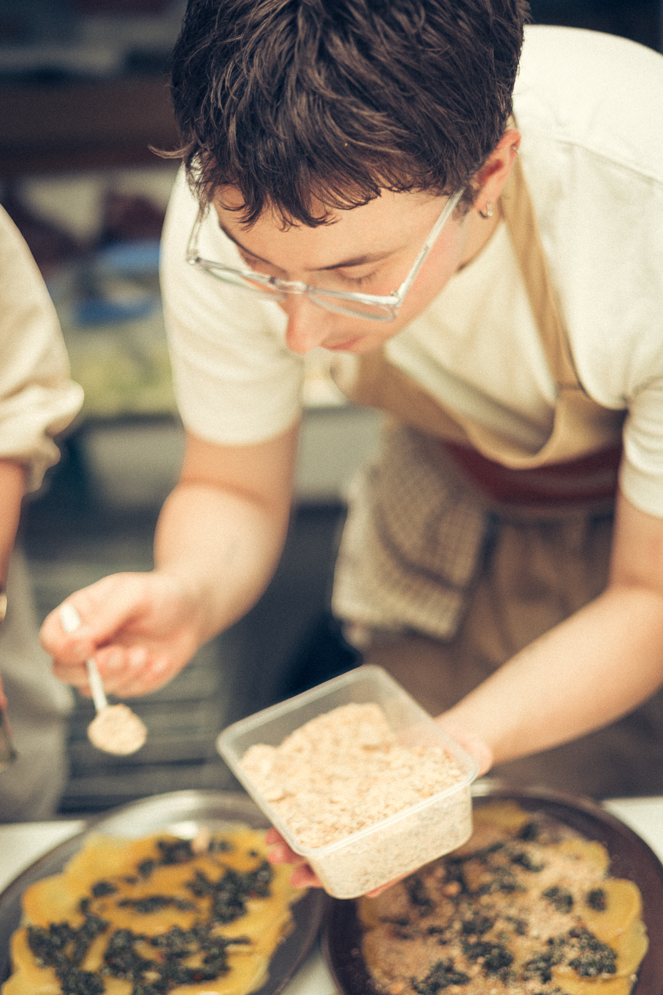Someone sprinkling toppings onto a freshly baked dessert.