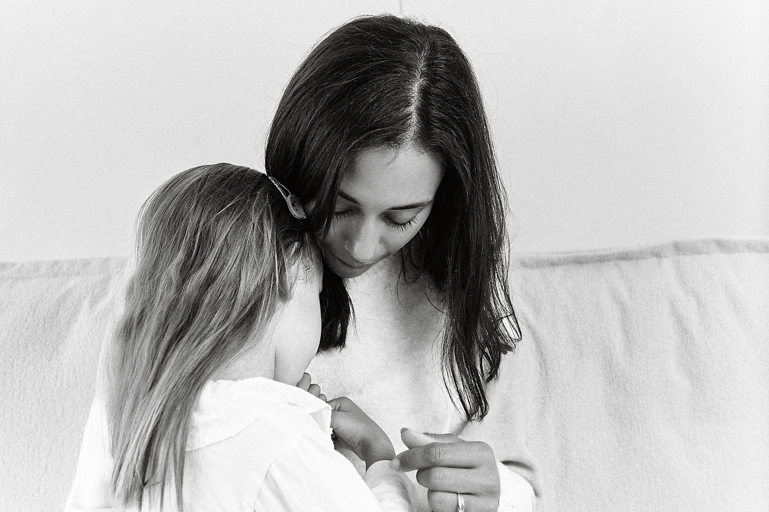 Black and white photo of a mother tenderly embracing her young daughter in a heartwarming moment.