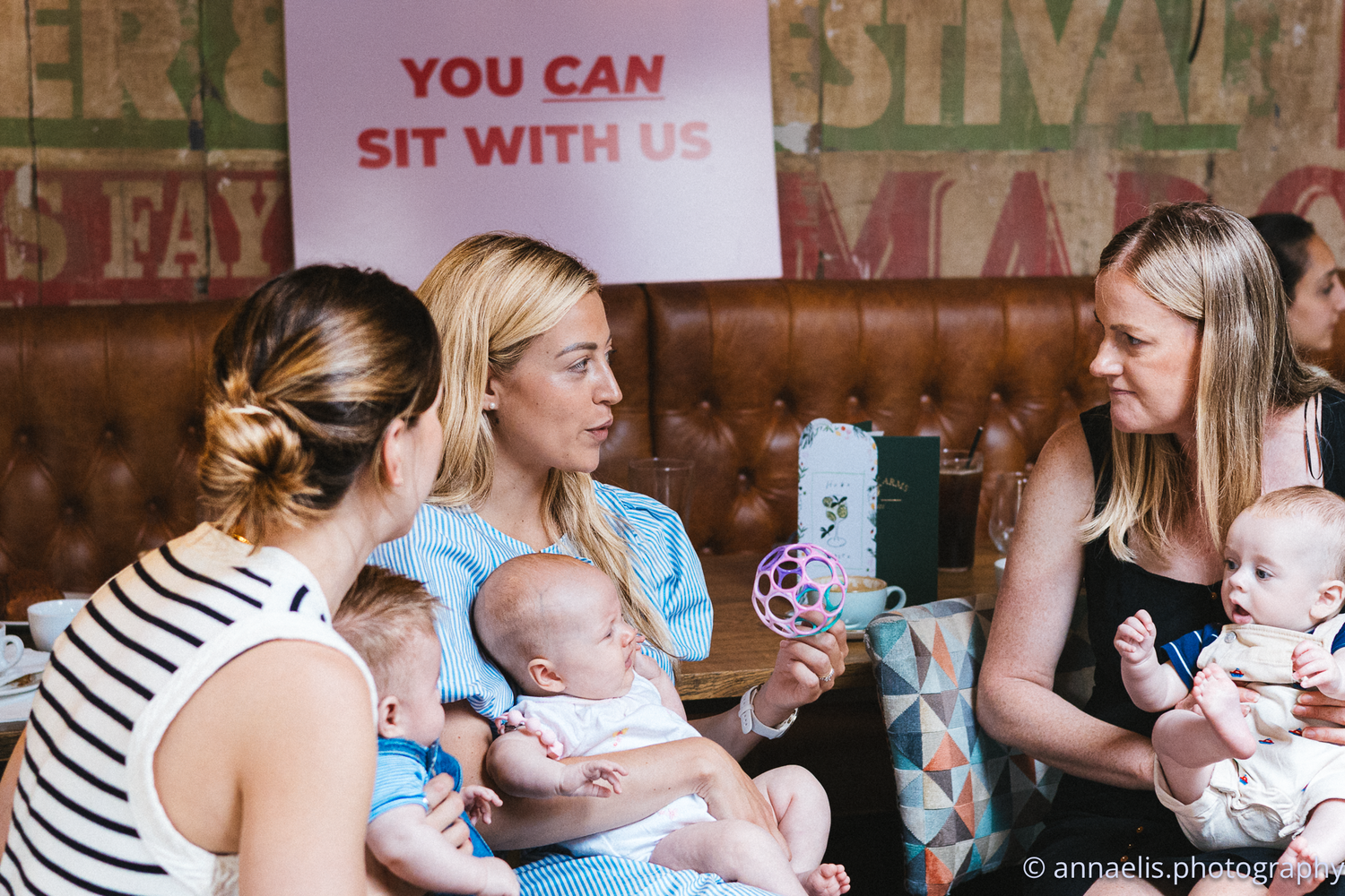 Social gathering space with signs reading 'You Can Sit With Us' on brick walls.