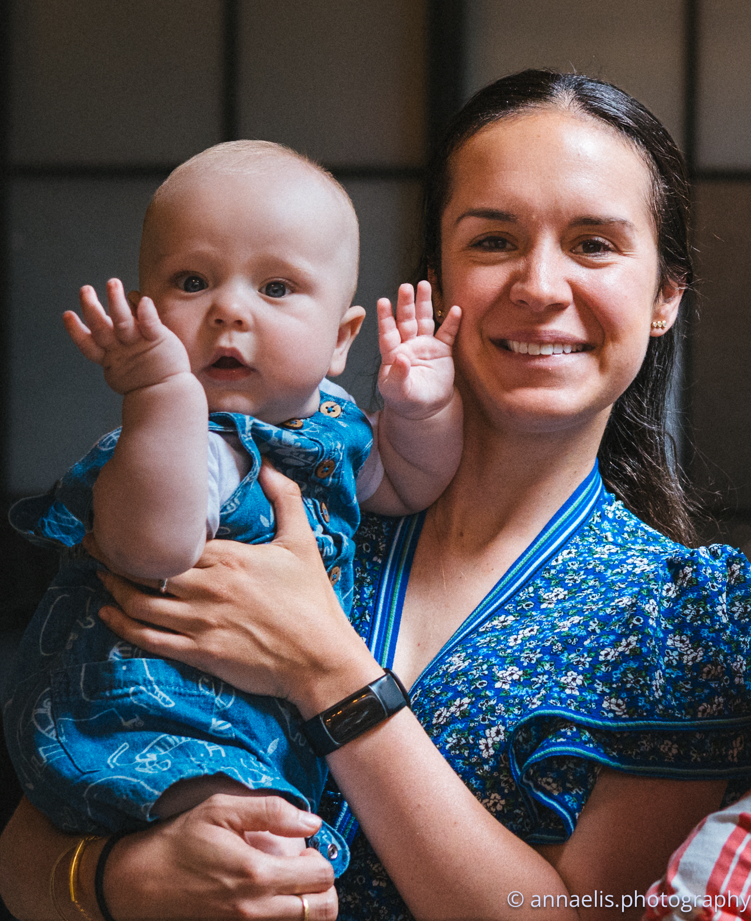 Parent in blue patterned top sharing joyful moments with infant.