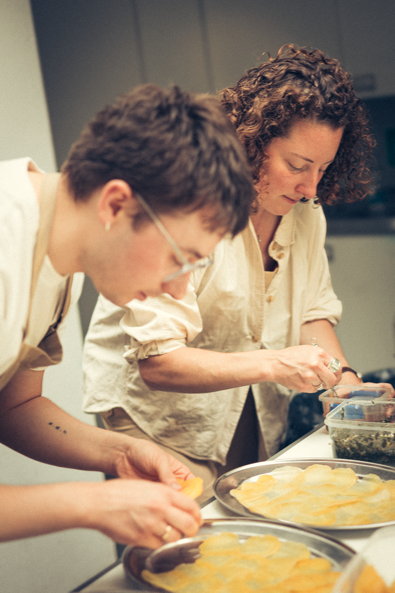 Chefs working together in kitchen preparing yellow custard or batter in round pans.