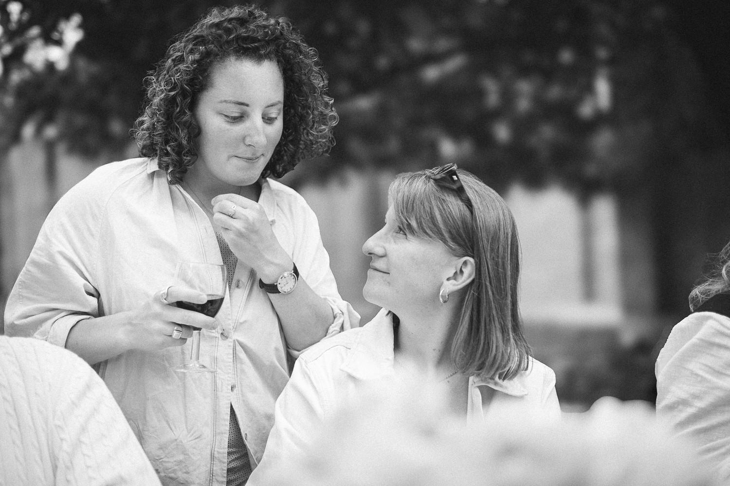Black and white photo of people engaged in conversation at an outdoor gathering.