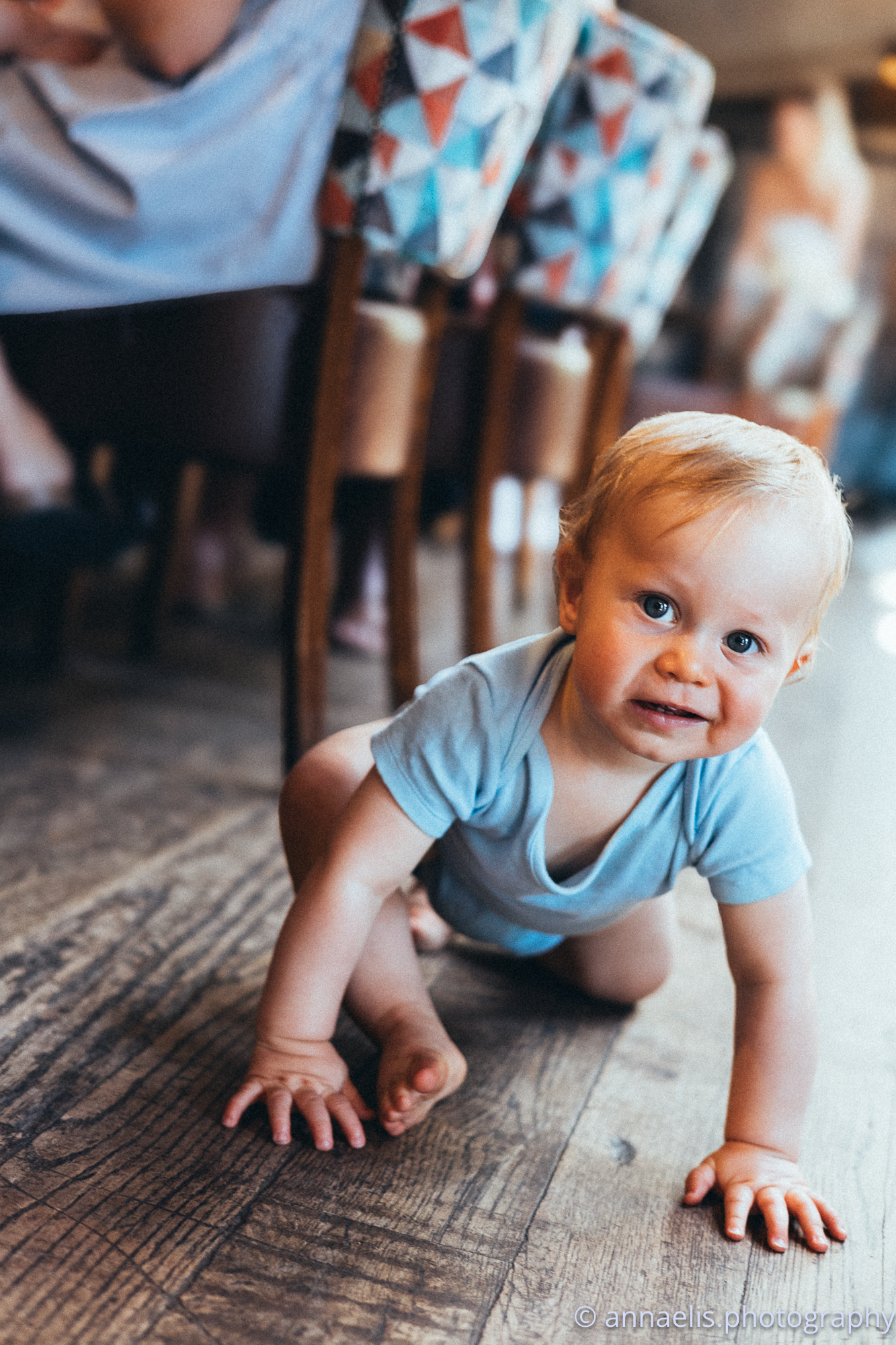 Baby crawling on wooden floor showing playful expressions in sequence.
