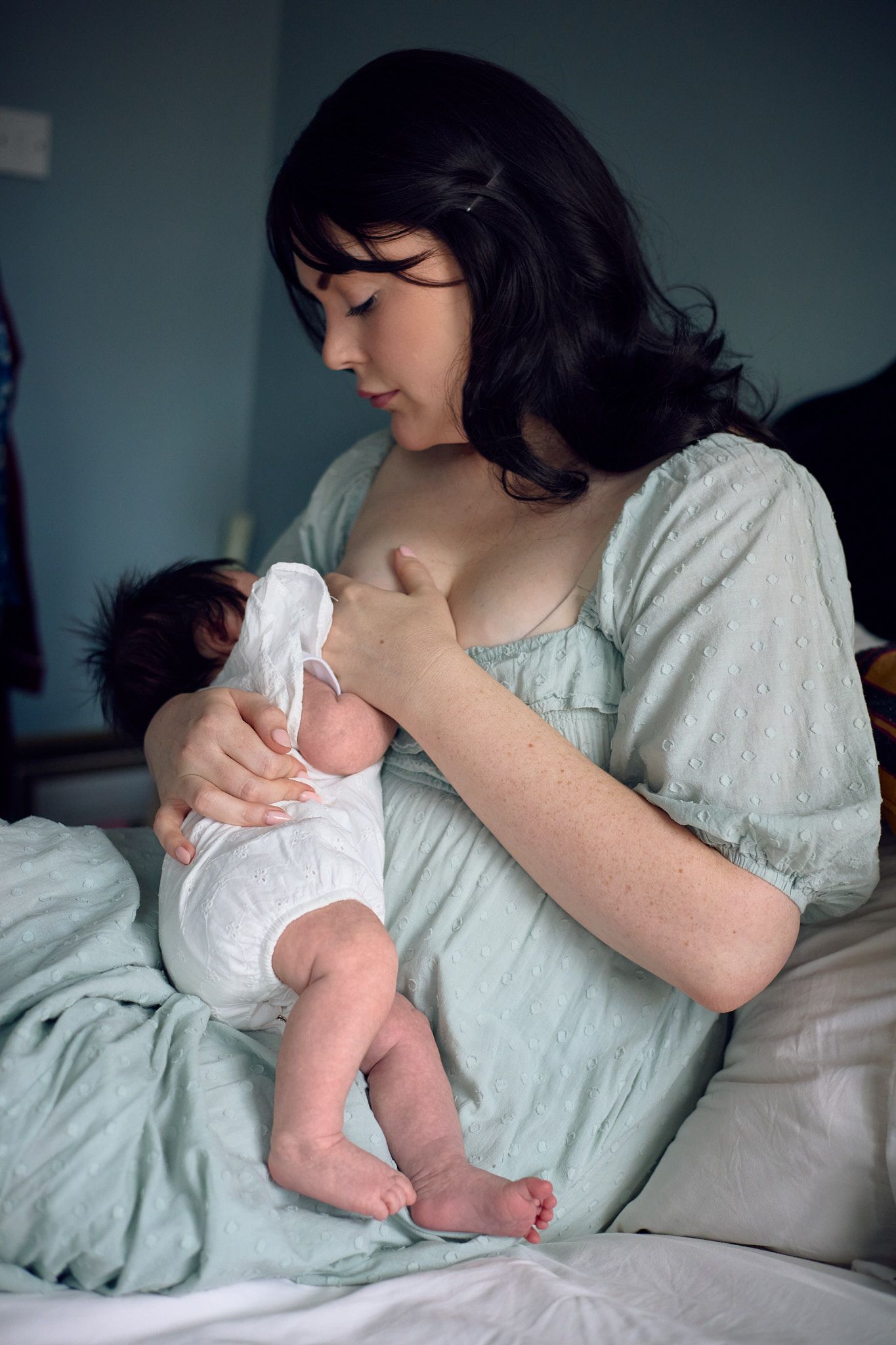 Tender moments captured between a caregiver in mint green and an infant in white.