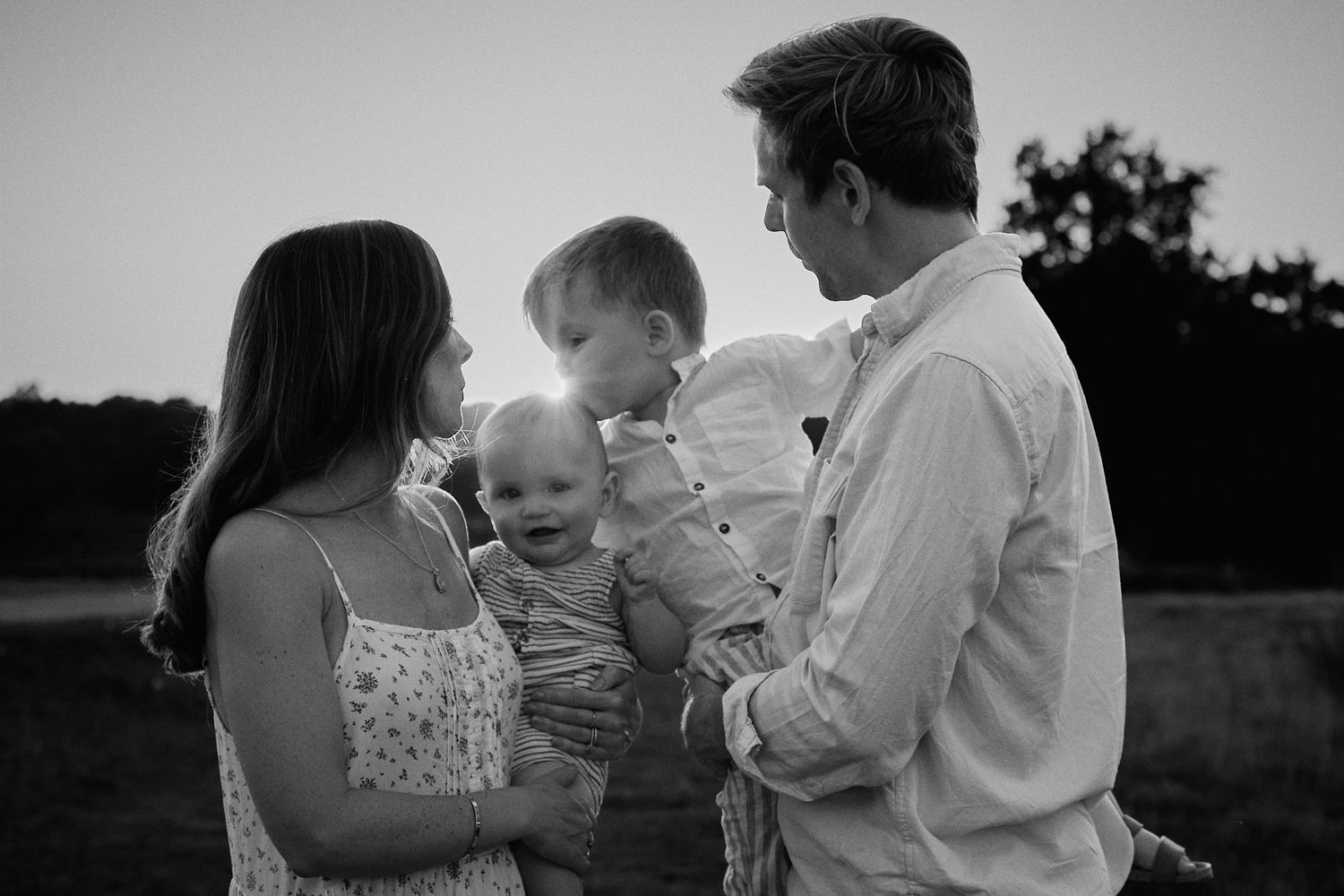 A family portrait in black and white showing tender moments together outdoors.