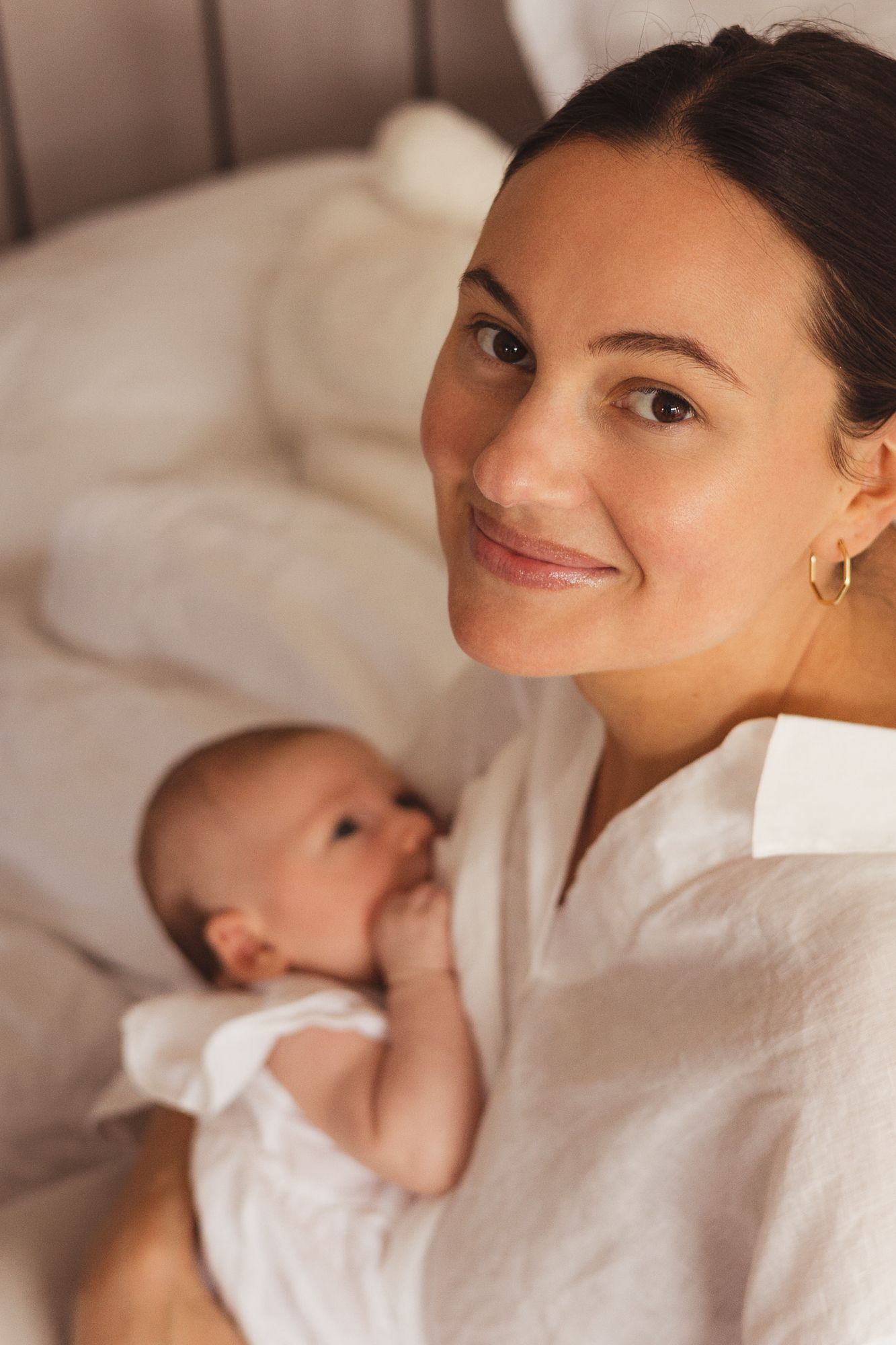 Mother in white shirt gazing lovingly at her newborn baby.