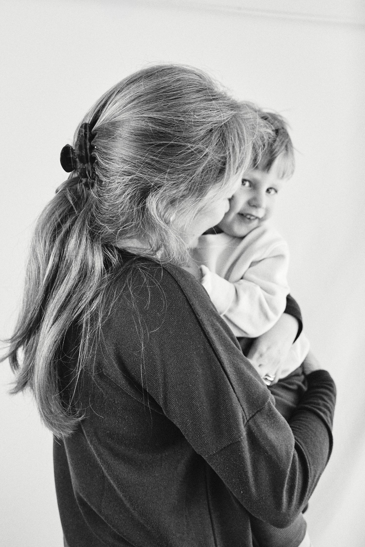 Black and white photo of a woman holding a smiling toddler, sharing a tender mother and child moment.