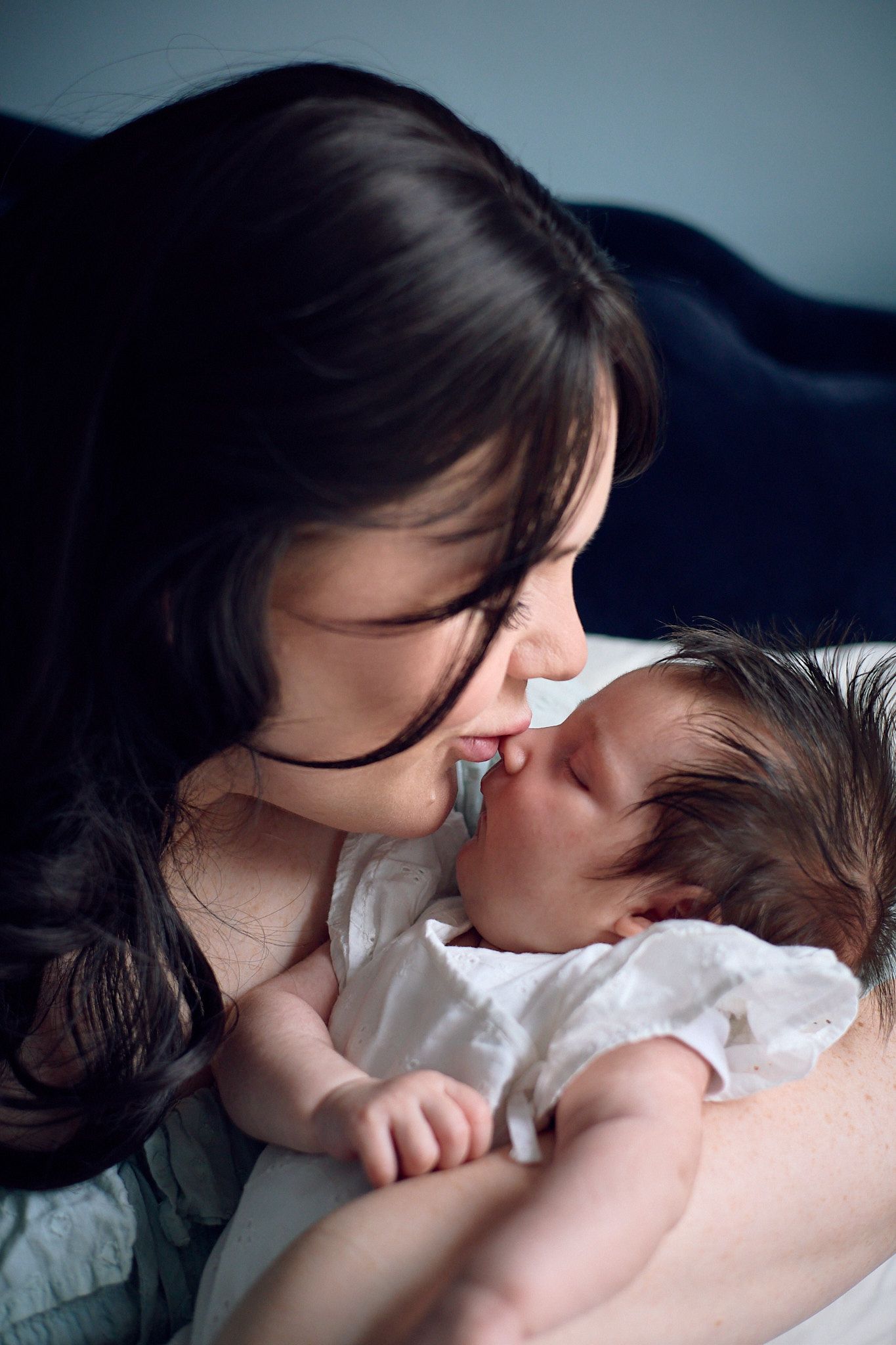 An intimate bonding moment between parent and infant on dark bedding.