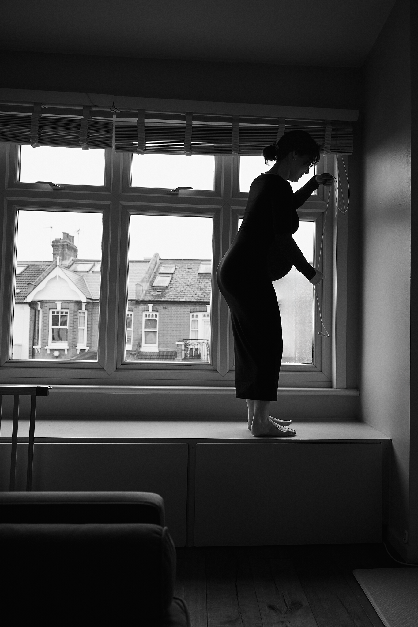 A series of black and white photos showing silhouettes of people working near windows in an empty room.