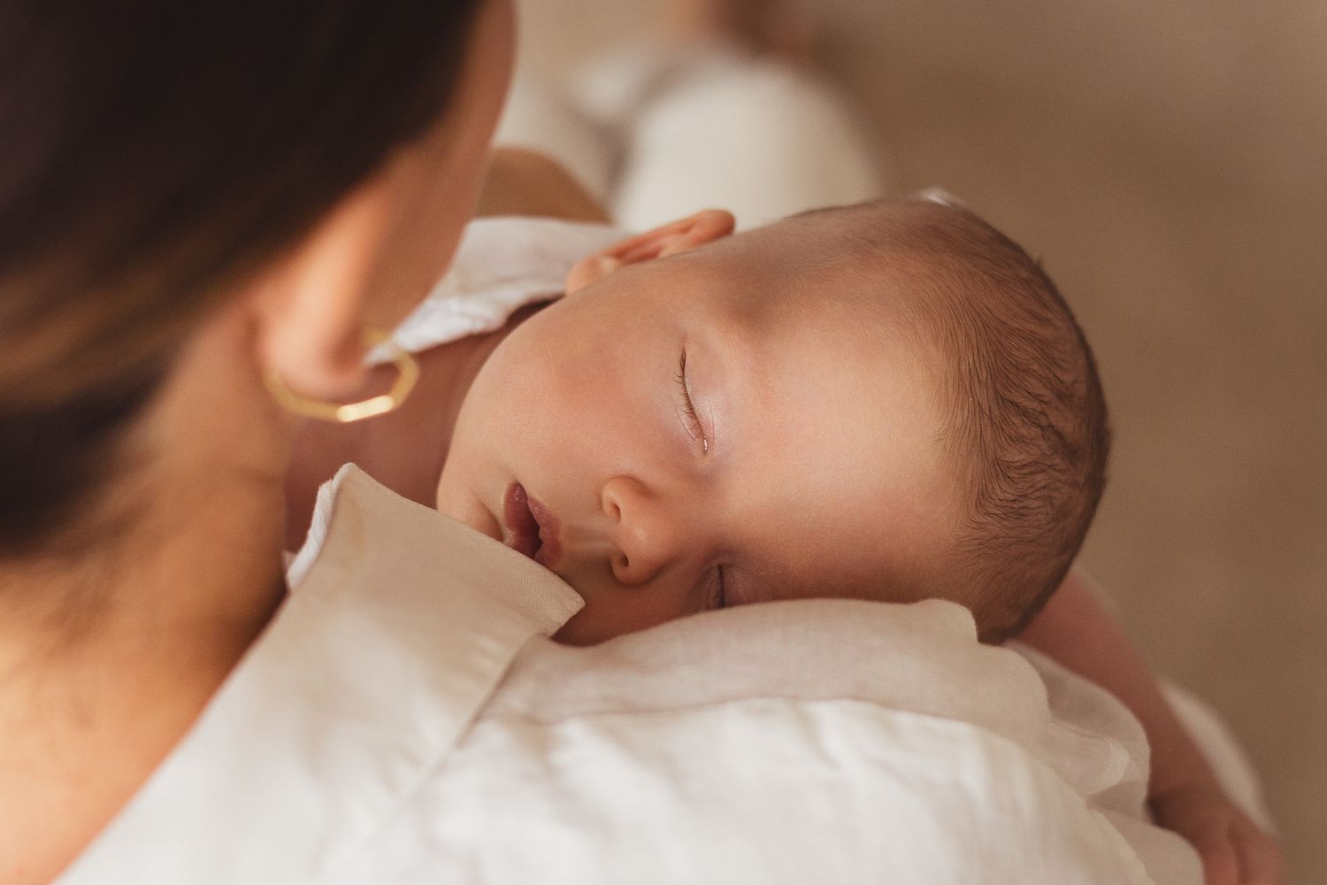 Tender moment between parent and infant in soft natural lighting.