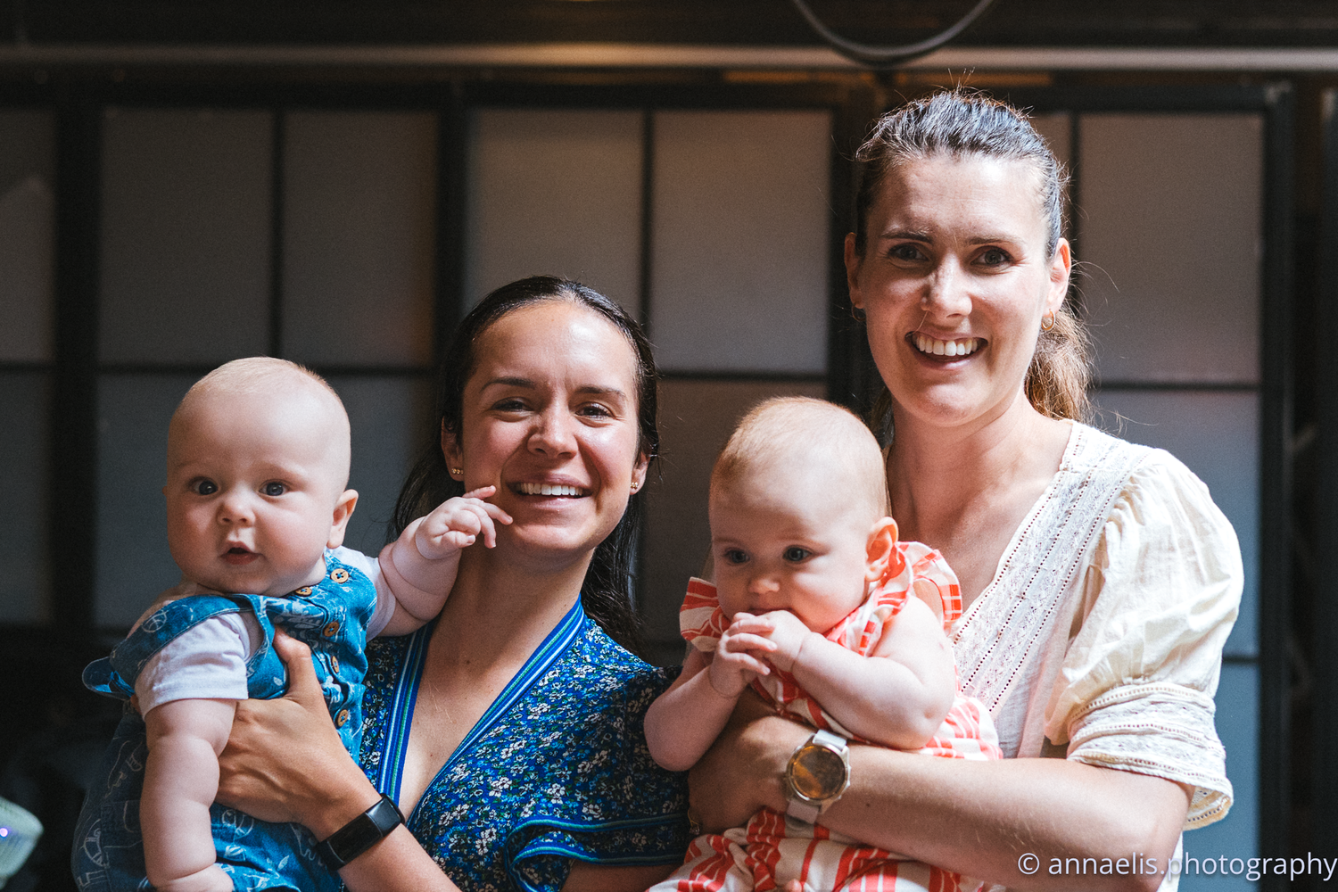 Group gathering at a social club with infants in casual setting.