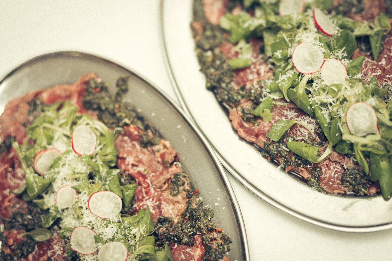 Close-up of elegant plated salads garnished with fresh radishes and greens.