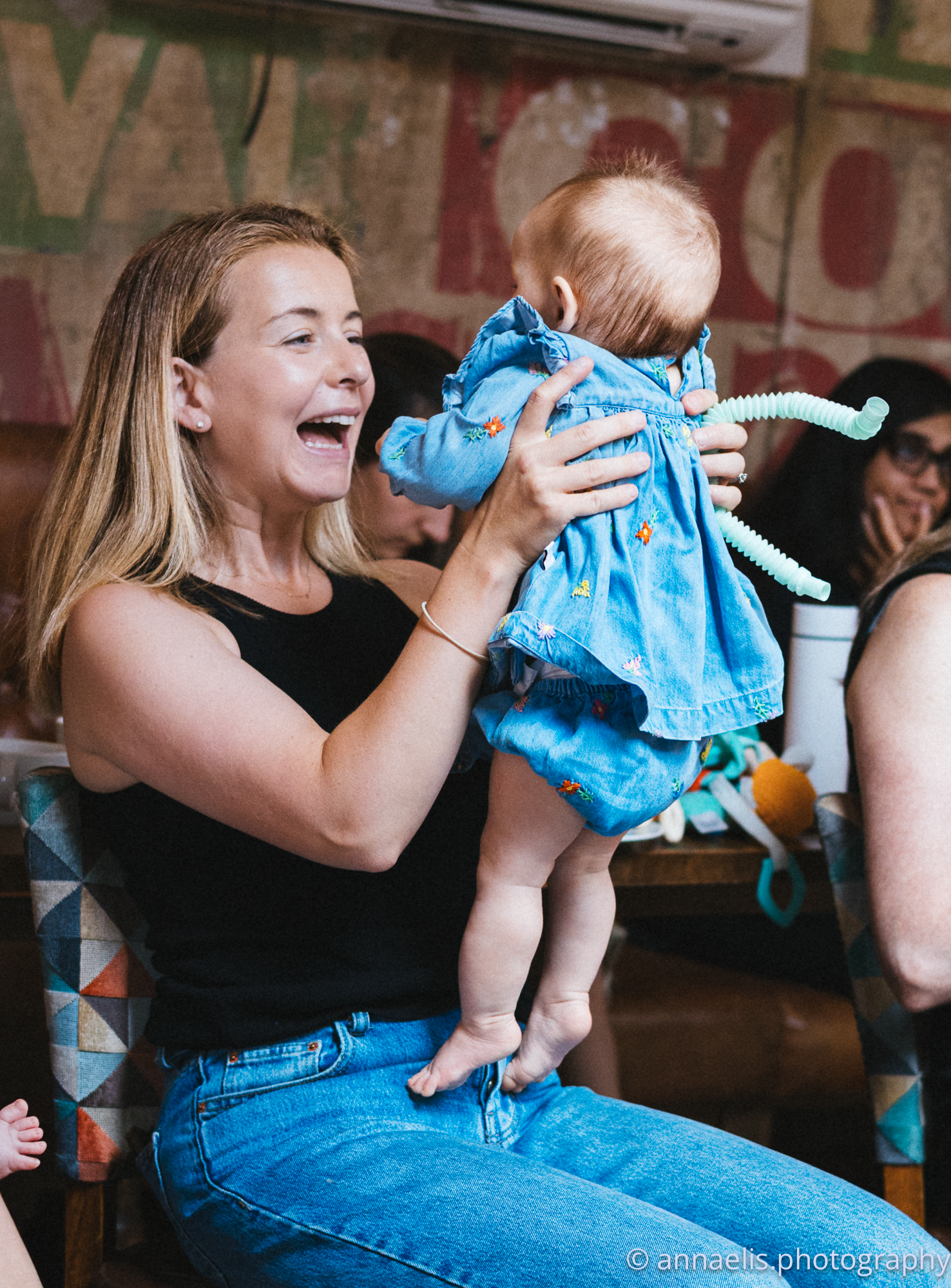 Playful interaction between parent and infant wearing blue outfit.