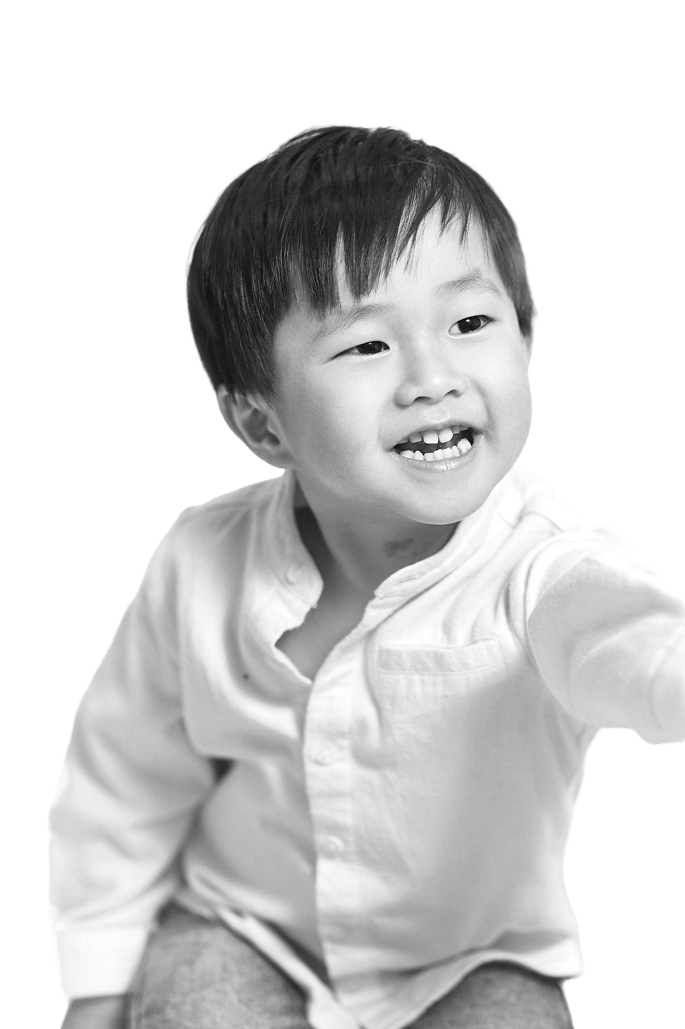 Black and white portrait of a smiling young Asian boy in a white shirt.