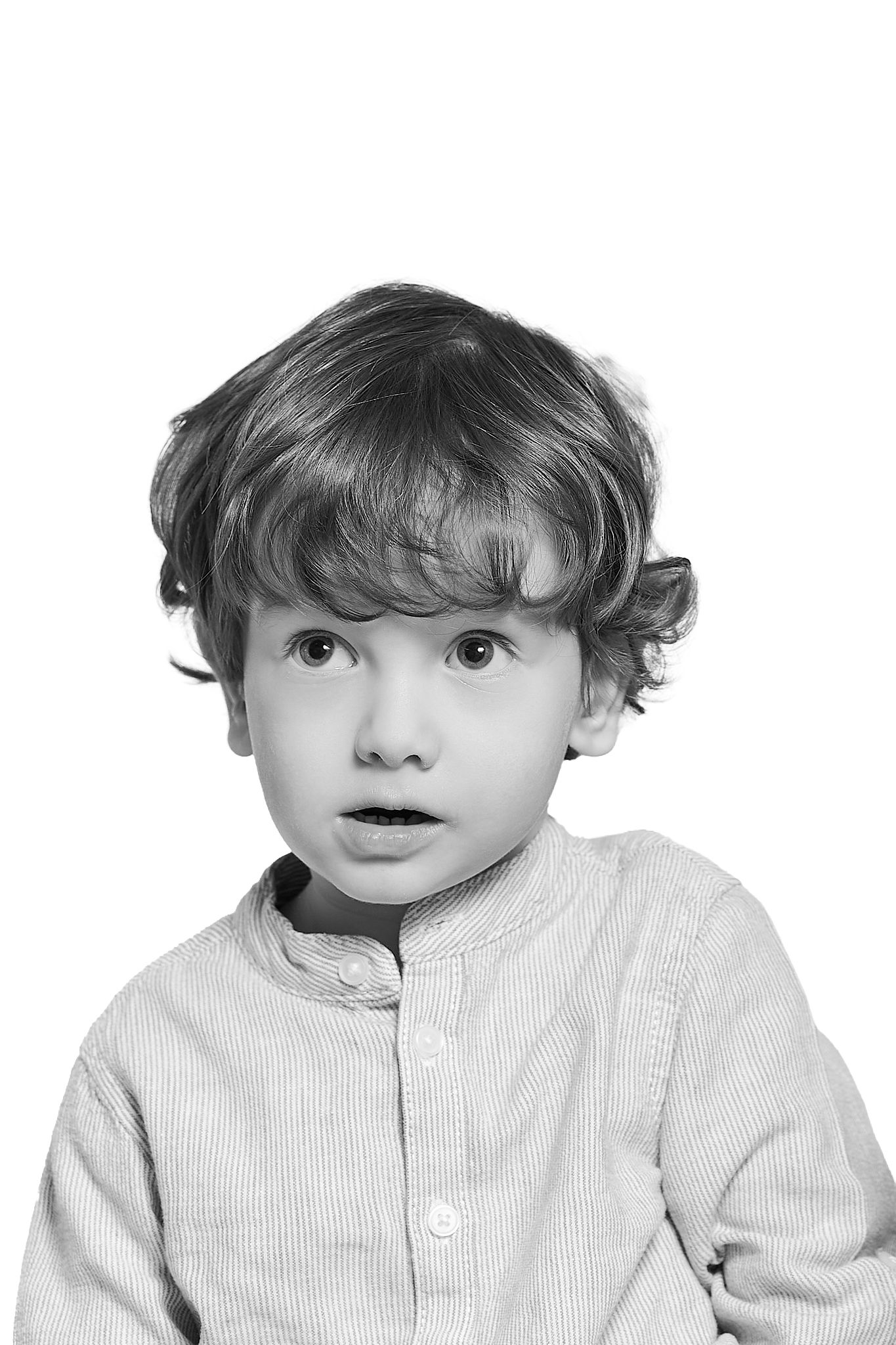 Black and white portrait of a surprised young toddler boy with curly hair wearing a button-up shirt.