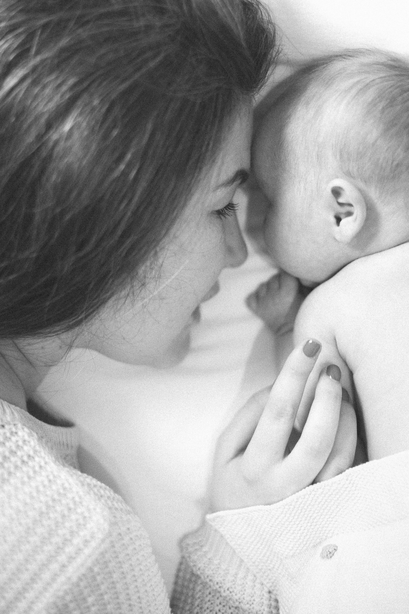 Intimate black and white portrait of parent and baby sharing a tender moment.