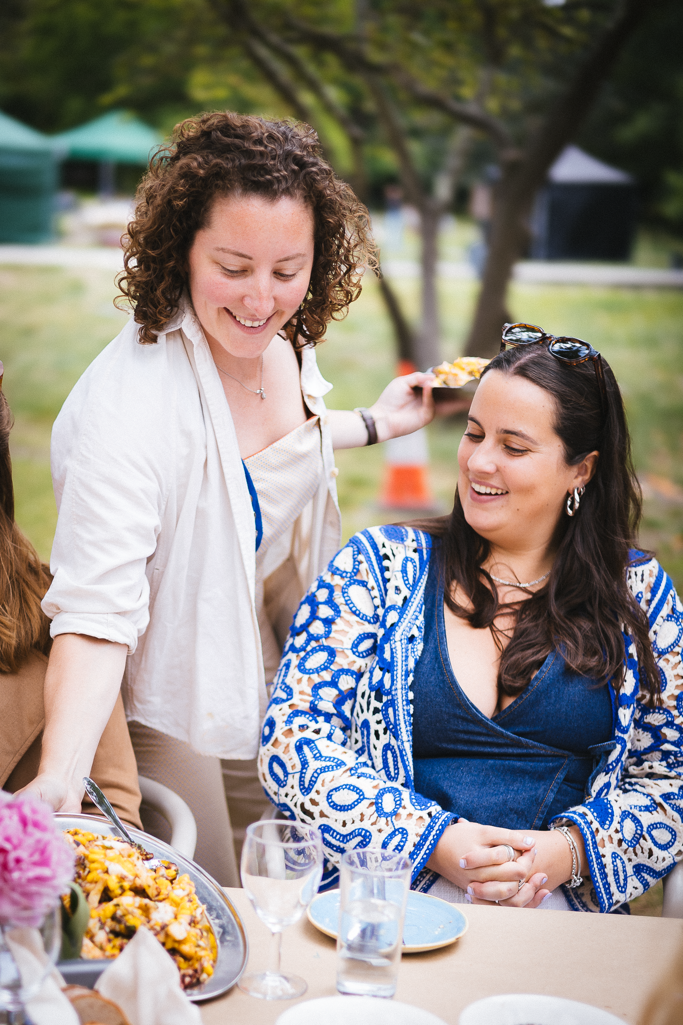 Guests enjoying food and conversation at an outdoor summer luncheon with floral decor.