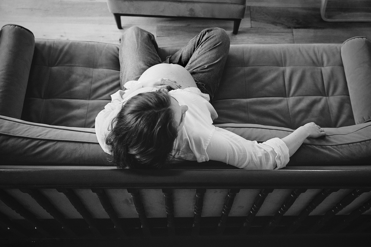 Black and white photo of a child lying on a leather sofa, resting peacefully in a cozy indoor setting.