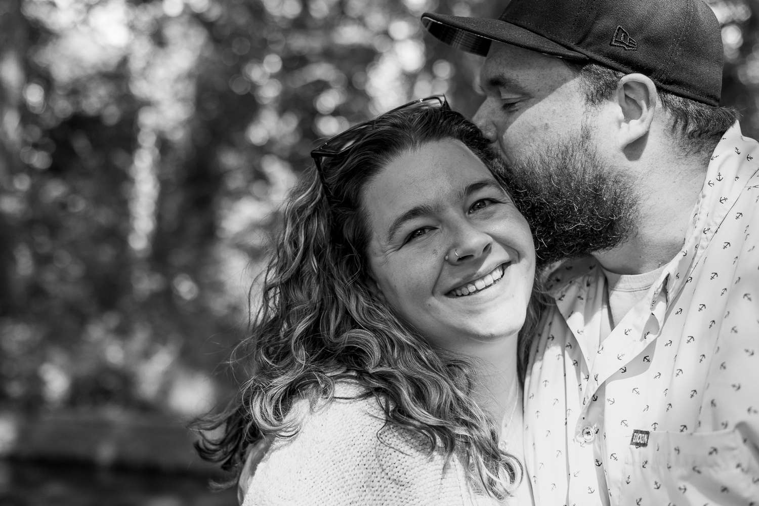 Intimate black and white portrait of couple sharing a tender moment outdoors.