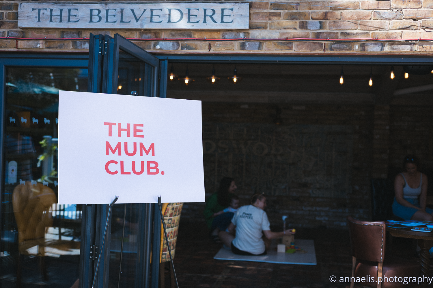 Exterior signage of The Belvedere and The Mum Club on brick wall.