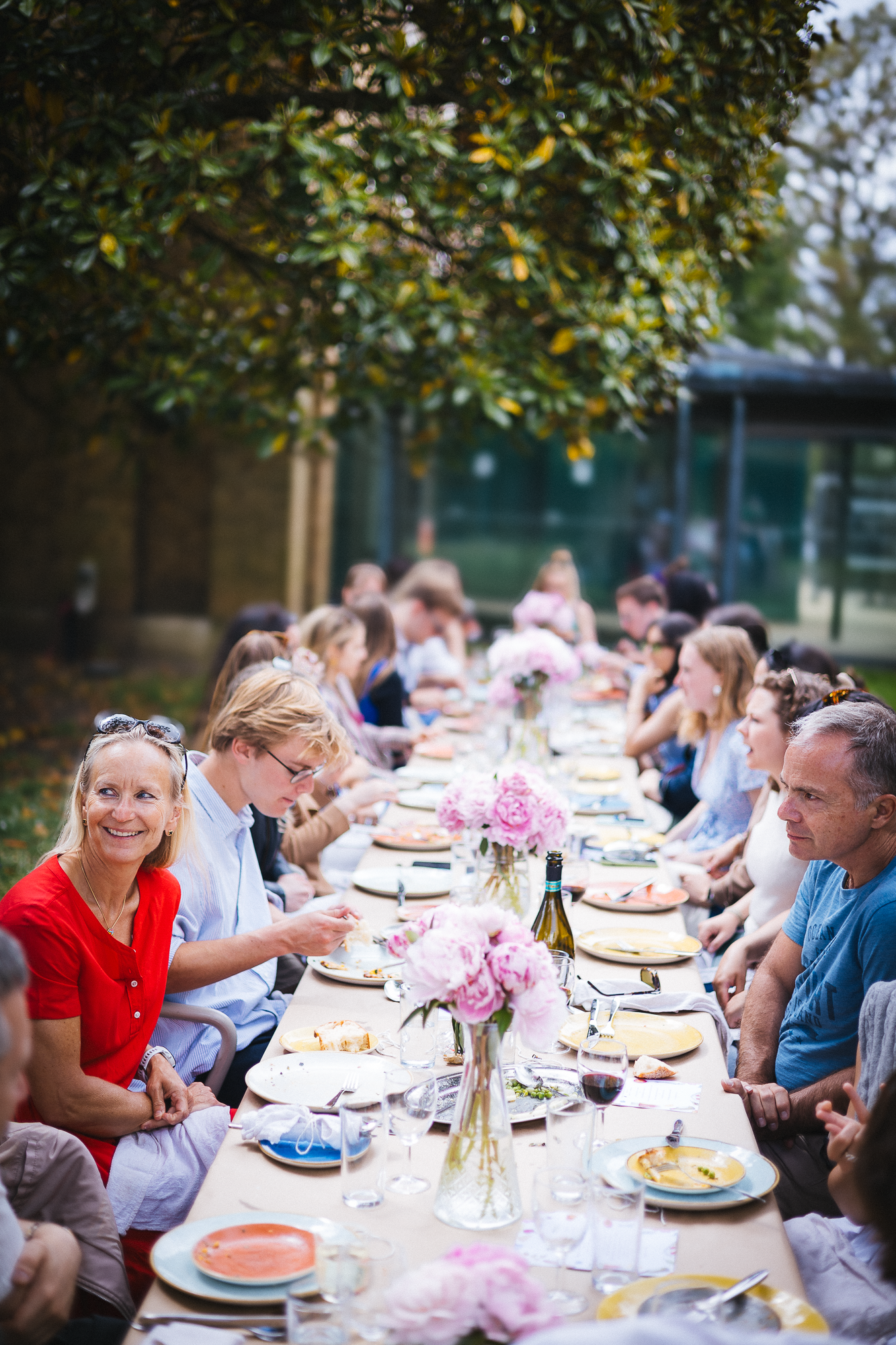 Long outdoor table setting with guests enjoying a festive garden party meal.